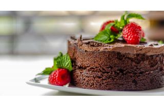 A rich, gluten-free chocolate cake topped with delicious chocolate frosting and fresh, vibrant raspberries.